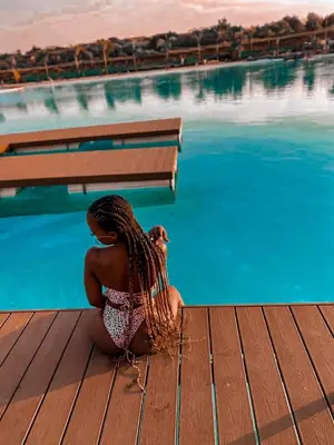 a woman sitting on a dock next to a swimming pool at The Blyde resort in Pretoria