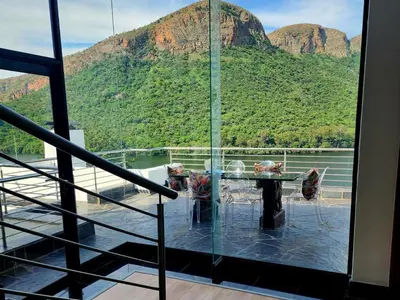 a room with a table and a view of a mountain at Hartbeespoort Lifestyle Guest House in Hartbeespoort