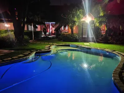 a swimming pool in a yard at night at Lipizzaner Lodge - Kyalami, Midrand in Kyalami