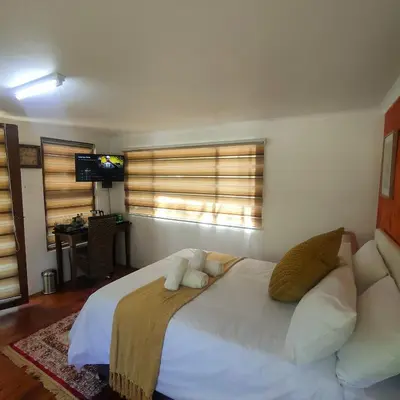 a bedroom with a large white bed and a desk at Lipizzaner Lodge - Kyalami, Midrand in Kyalami