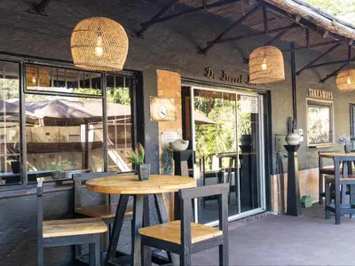 a restaurant with a wooden table and chairs and windows at Eco Lodge Lephalale in Lephalale