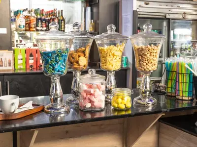a counter with four glass vases filled with different types of food at Eco Lodge Lephalale in Lephalale