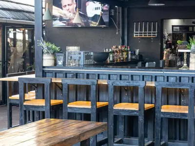 a bar with four wooden stools and a counter at Eco Lodge Lephalale in Lephalale