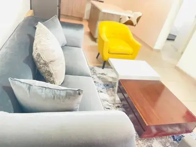 a living room with a gray couch and a yellow chair at Priceless 2Bed, Pool, Gym, Wifi in Midrand