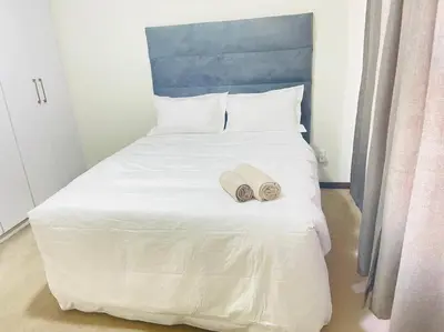 a large white bed with two towels on it at Priceless 2Bed, Pool, Gym, Wifi in Midrand