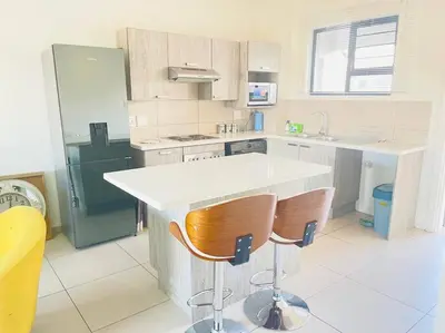 a kitchen with a white counter and two chairs at Priceless 2Bed, Pool, Gym, Wifi in Midrand