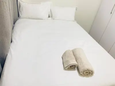 a white bed with two towels on it at Priceless 2Bed, Pool, Gym, Wifi in Midrand