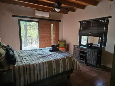 a bedroom with a bed and a mirror and a window at Amani Milele (Everlasting Peace) in Marloth Park