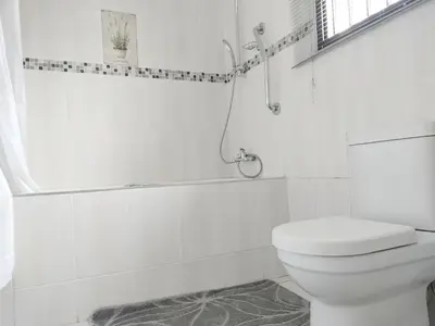 a white bathroom with a toilet and a shower at Sunrise Guesthouse in Pretoria