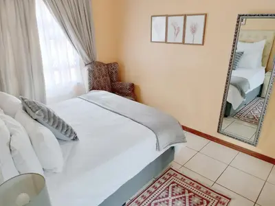 a bedroom with a white bed and a mirror at Sunrise Guesthouse in Pretoria