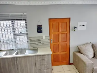 a kitchen with a sink and a couch and a door at Sunrise Guesthouse in Pretoria