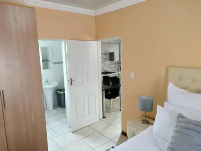 a bedroom with a bed and a bathroom with a sink at Sunrise Guesthouse in Pretoria