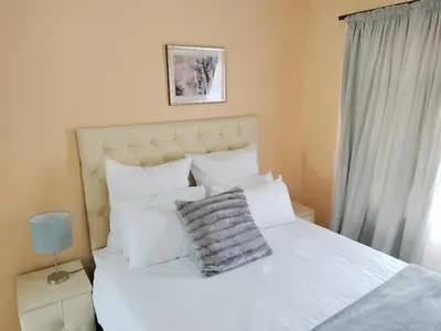 a bedroom with a white bed with white pillows at Sunrise Guesthouse in Pretoria