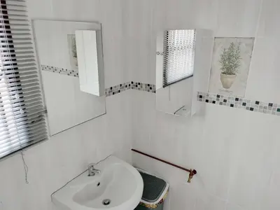 a white bathroom with a sink and a mirror at Sunrise Guesthouse in Pretoria