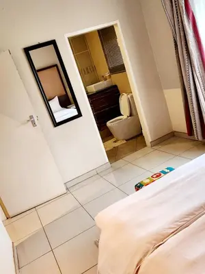 a bedroom with a bed and a bathroom with a mirror at MAKWATAMBANI GUEST MANOR in Thohoyandou