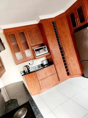 a small kitchen with wooden cabinets and a sink at MAKWATAMBANI GUEST MANOR in Thohoyandou