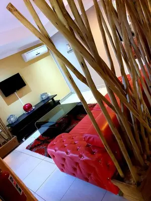 a living room with a red couch and a tv at MAKWATAMBANI GUEST MANOR in Thohoyandou