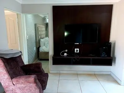 a living room with a tv and a chair at R&R GUEST HOUSE in Lenyenye