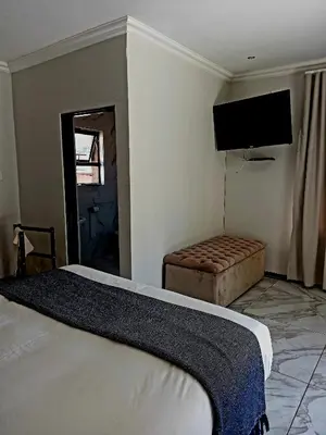 a bedroom with a bed and a flat screen tv at R&R GUEST HOUSE in Lenyenye