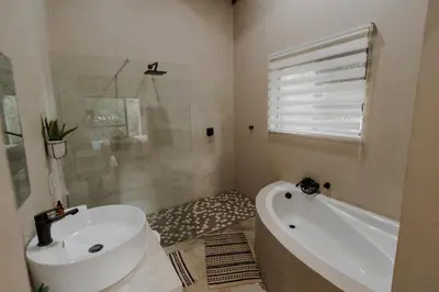 a bathroom with a tub and a sink and a bath tub at Afri Villa Stays - Luxury Bush Villa Hyena in Marloth Park