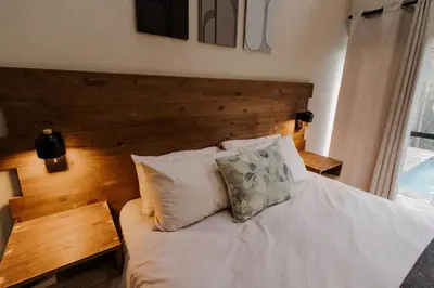 a bedroom with a white bed with a wooden headboard at Afri Villa Stays - Luxury Bush Villa Hyena in Marloth Park