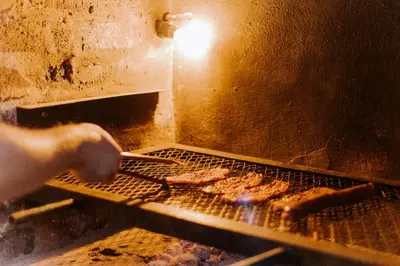 a person is cooking meat on a grill at Afri Villa Stays - Luxury Bush Villa Hyena in Marloth Park