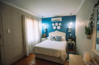 a bedroom with blue walls and a white bed at Blue Bell Guesthouse in Tzaneen