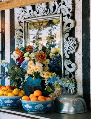 a mirror and two bowls of oranges and flowers at Blue Bell Guesthouse in Tzaneen