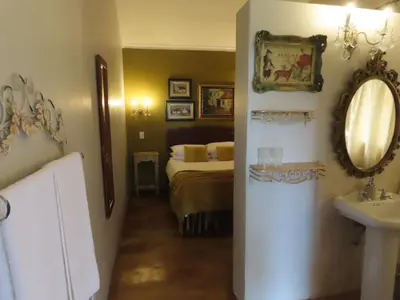 a bedroom with a bed and a sink and a mirror at Blue Bell Guesthouse in Tzaneen