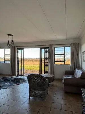 a living room with a couch and a table and windows at Dewdrop Farm Stay in Ermelo