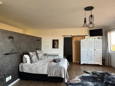 a bedroom with a bed with a gray wall at Dewdrop Farm Stay in Ermelo