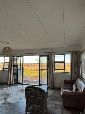 a living room with a couch and views of a field at Dewdrop Farm Stay in Ermelo