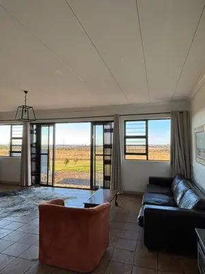 a living room with a couch and some windows at Dewdrop Farm Stay in Ermelo