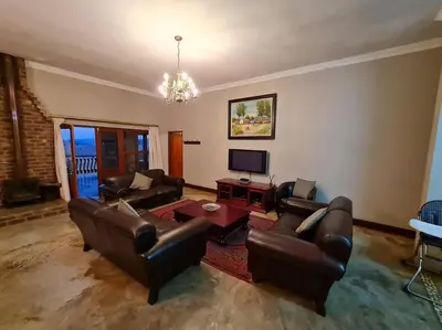 a living room with leather couches and a television at Stone Castle, Dullstroom Country Estate in Dullstroom