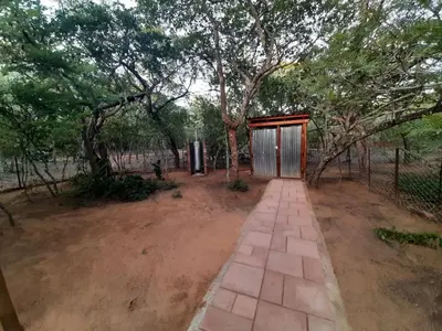 a smallshed in a field with trees and a dirt road at VlakkiesKraal Bosbok Camp in Bela-Bela