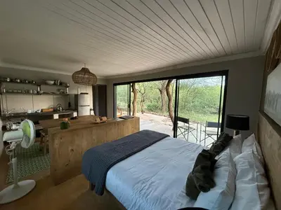 a bedroom with a bed and a large window at Bushveld Bivouac Private Camp in Mica