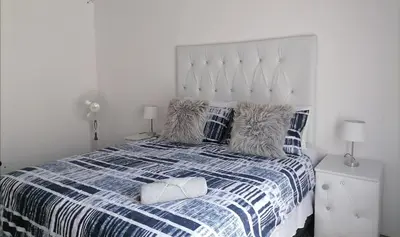 a white bedroom with a blue and white bed with pillows at Drakensview guesthouse in Acornhoek