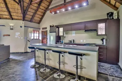 a kitchen with a counter with stools at a bar at Kruger Escape - Solar System in Marloth Park