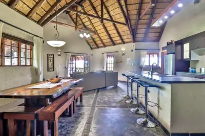 a large kitchen with a wooden table and stools at Kruger Escape - Solar System in Marloth Park