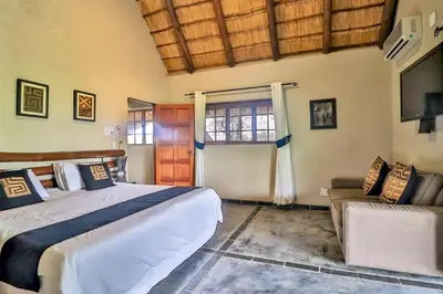 a bedroom with a large bed and a couch at Kruger Escape - Solar System in Marloth Park