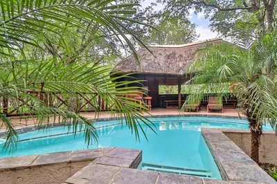 a swimming pool in front of a house at Kruger Escape - Solar System in Marloth Park