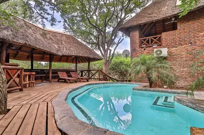a house with a swimming pool and a wooden deck at Kruger Escape - Solar System in Marloth Park
