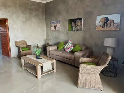 a living room with a couch and a table and chairs at The Barnhouse in Hammanskraal