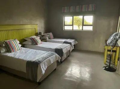 a bedroom with three beds and a window at The Barnhouse in Hammanskraal