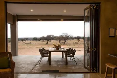 a dining room with a table and chairs and a field at The Barnhouse in Hammanskraal