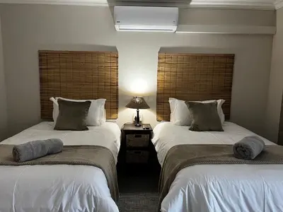 two beds in a room with a lamp on a table at Moya-Sky in Komatipoort