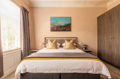 a bedroom with a large bed and a painting on the wall at House Firefly Muckleneuk - Furnished House in Pretoria