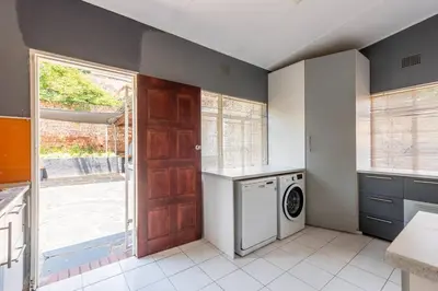 a kitchen with a washer and dryer next to a door at House Firefly Muckleneuk - Furnished House in Pretoria