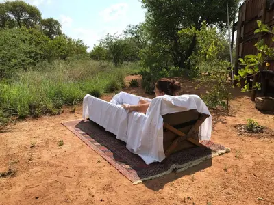 a woman sitting in a bath tub on the dirt at Out in Africa Wildlife Lodge in Dinokeng Game Reserve