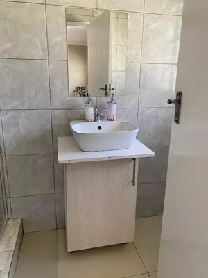 a bathroom with a sink and a mirror at The Manor in Midrand